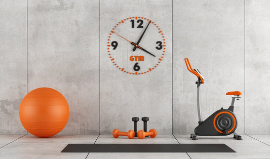 a concrete room with orange gym equipment and a large clock on the wall
