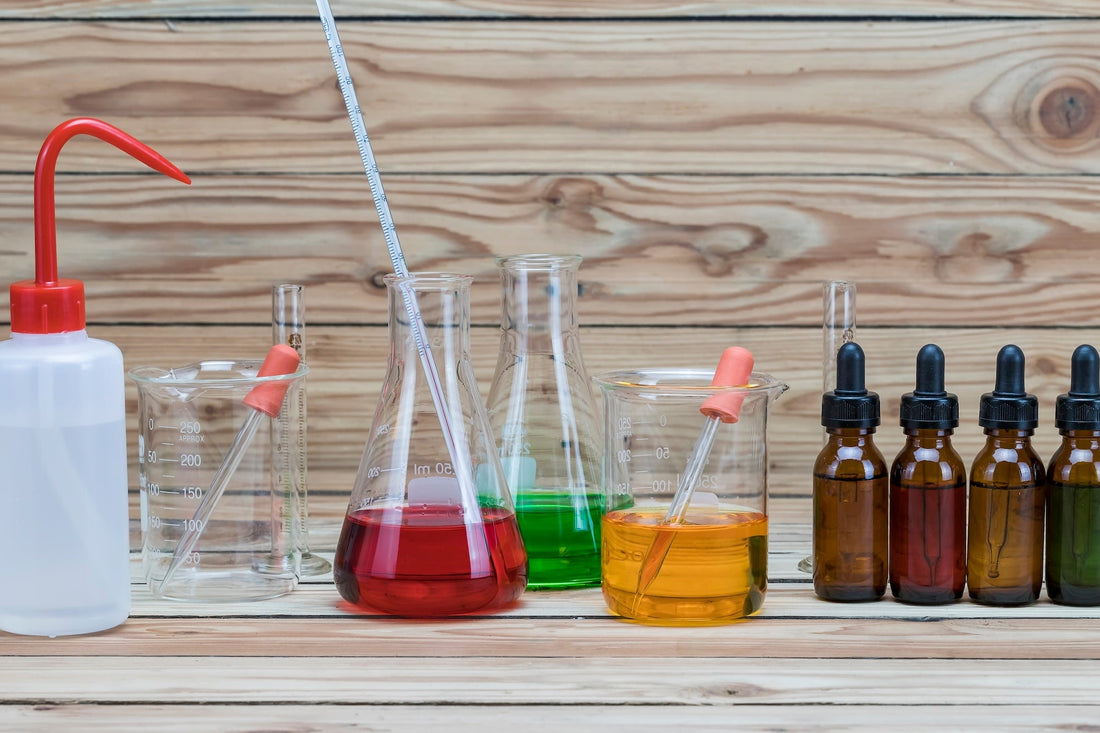 several chemical containers with colored liquids in front of a wood backdrop