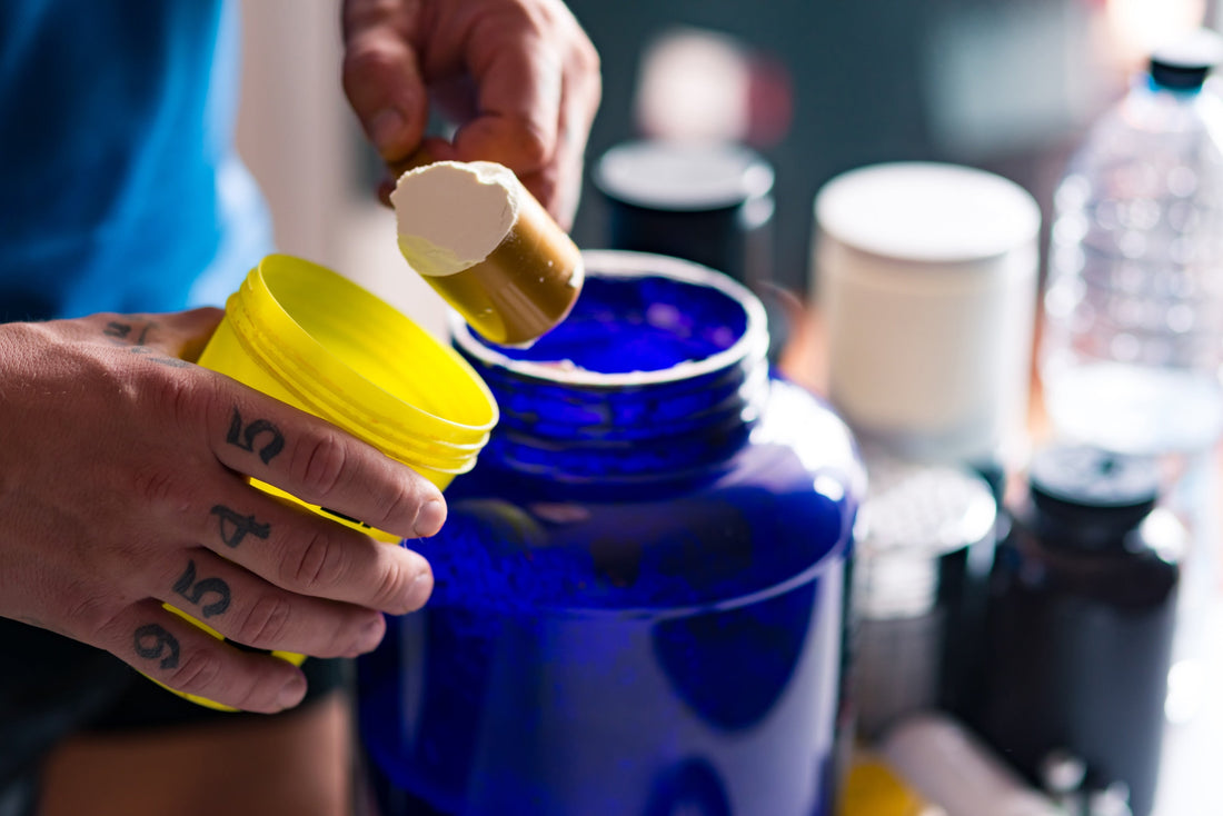 a man scooping powder from a blue jar into a yellow cup