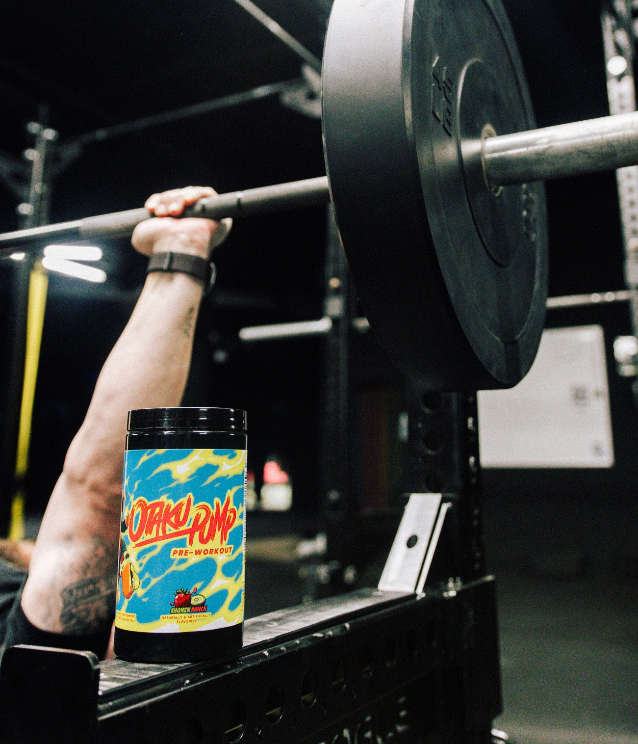 A tub of Otaku Pump Shonen Punch with someone bench-pressing in the background
