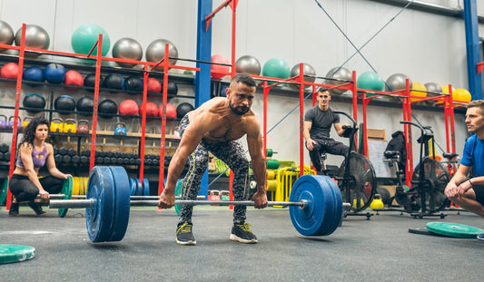 a shirtless man doing deadlifts in a commercial gym